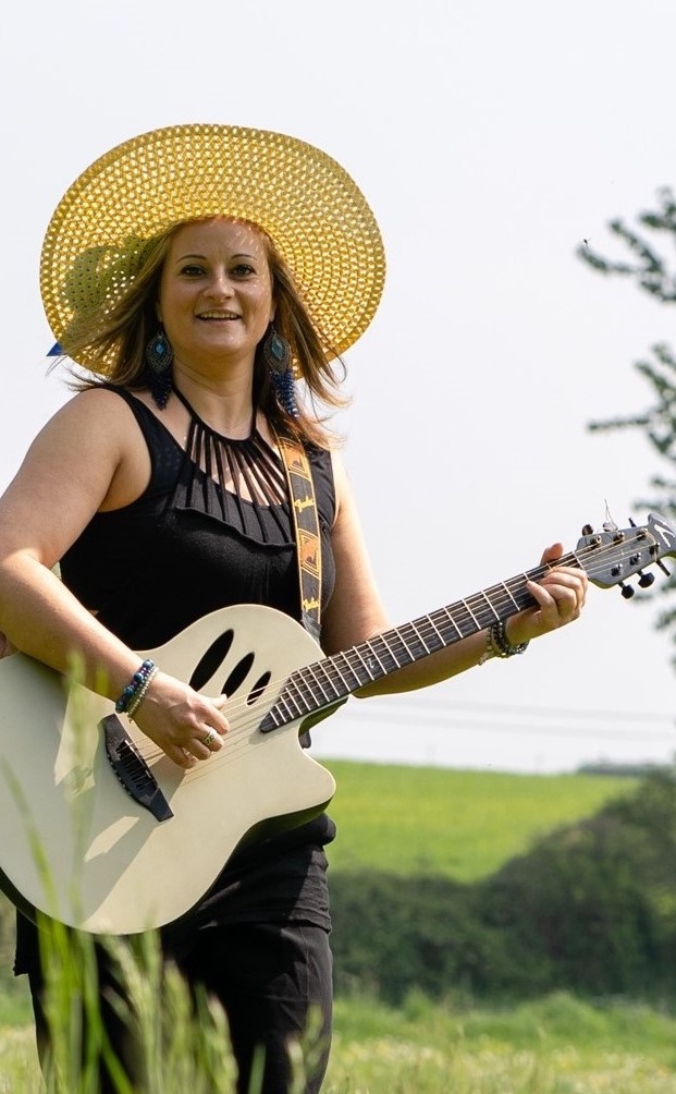 Foto: Michael Kestin, Marta Latour mit Gitarre und Sonnenhut
